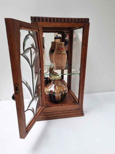 Eikenhouten hangvitrine ingericht met vintage aardewerk vazen op glazen legplank